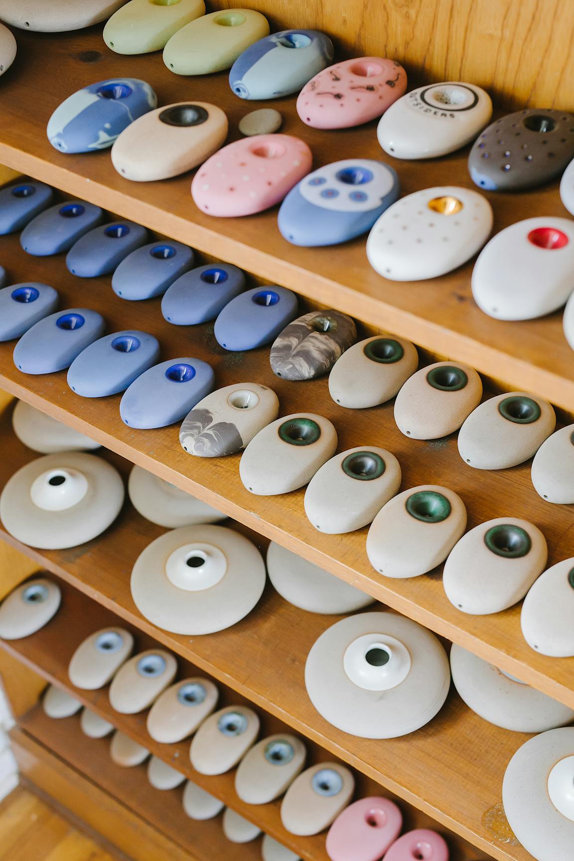 Rows of wooden shelves hold dozens of curvy ceramic pipes.